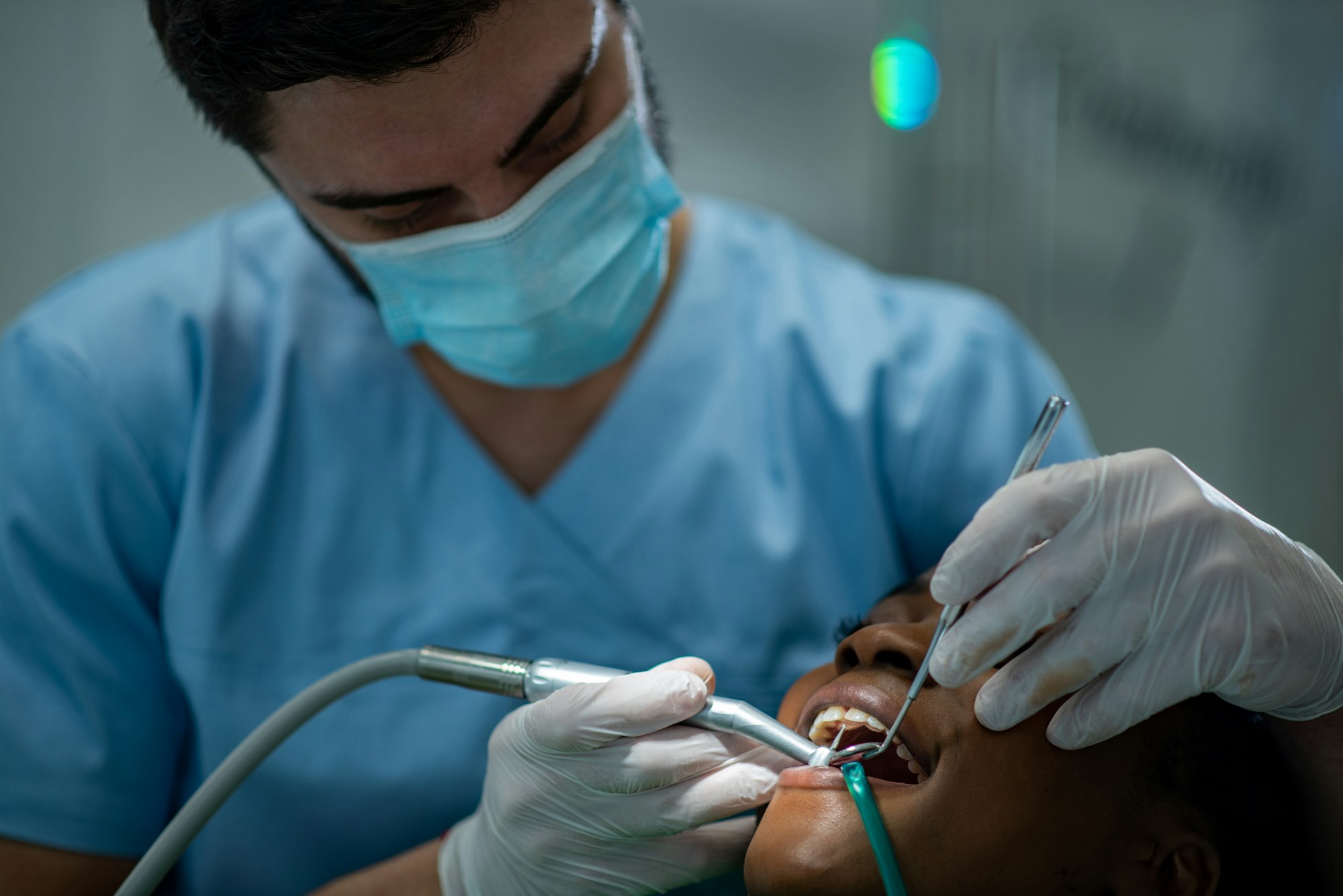 Dentist providing dental care treatment to a african american female patient
