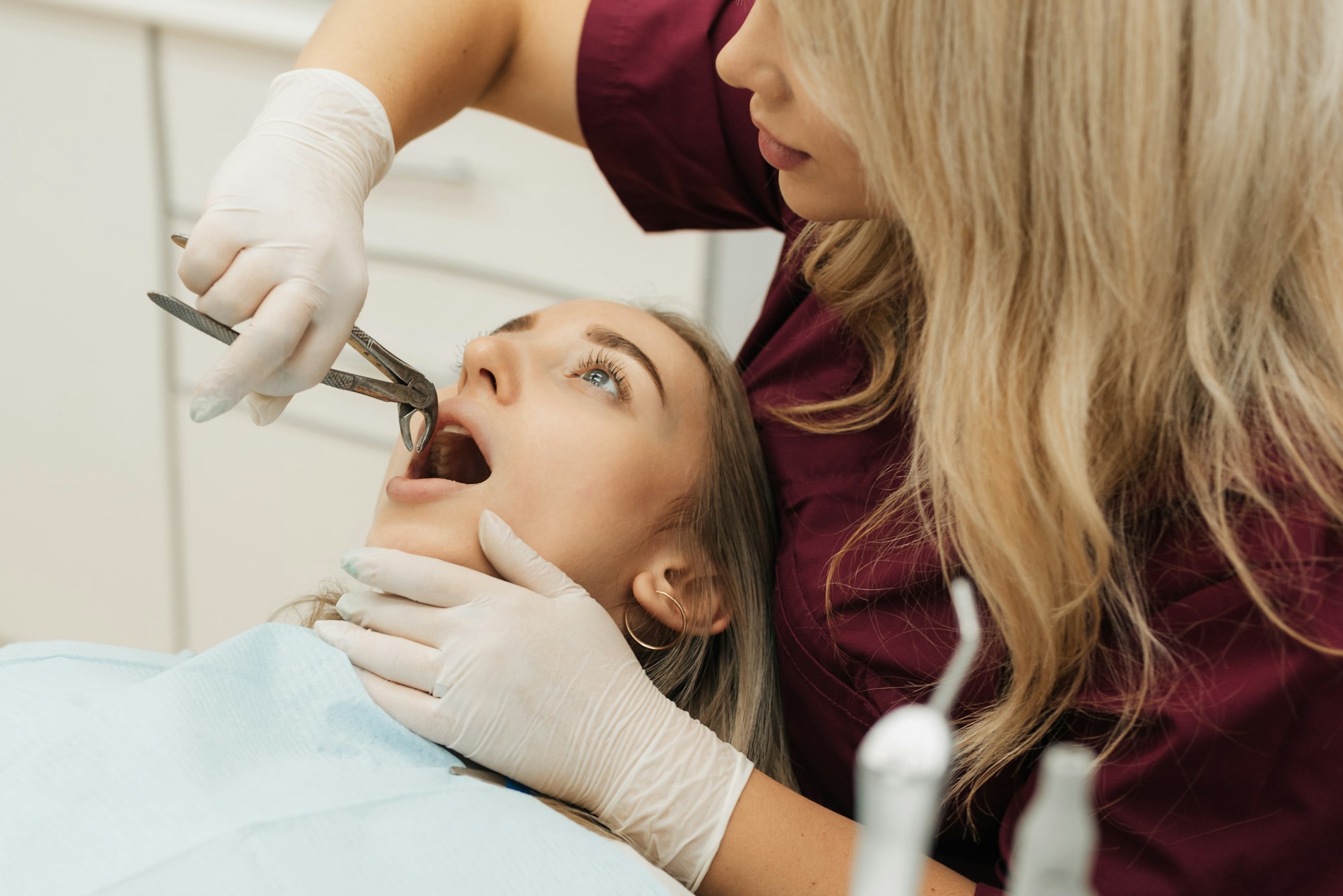 Dentist using surgical pliers to remove a decaying tooth in clinic
