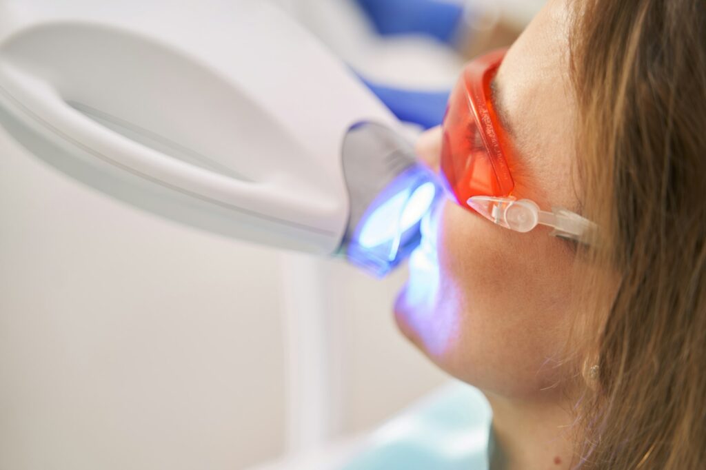 Woman receiving laser whitening treatment in dental clinic